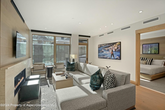 living room featuring light hardwood / wood-style floors, a wall of windows, and a high end fireplace