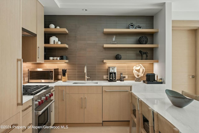 bar featuring light stone countertops, sink, decorative backsplash, light brown cabinetry, and appliances with stainless steel finishes