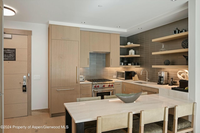 kitchen featuring kitchen peninsula, tasteful backsplash, stainless steel appliances, sink, and a breakfast bar area