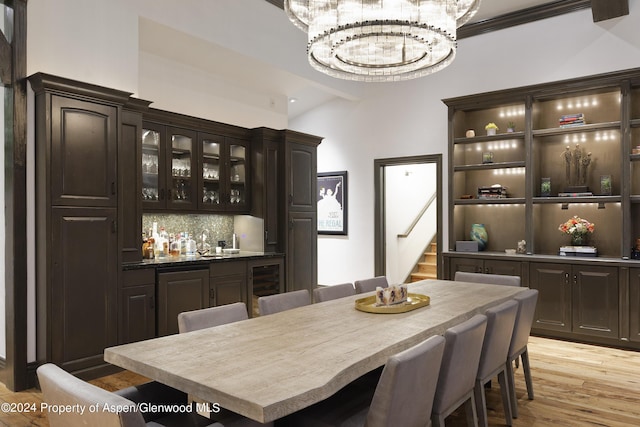 dining space with vaulted ceiling, beverage cooler, sink, a chandelier, and light hardwood / wood-style floors