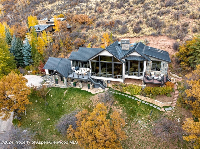 back of property with a sunroom, an outdoor living space, a lawn, a wooden deck, and a patio