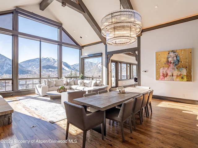 dining space with hardwood / wood-style floors, a mountain view, beam ceiling, and a chandelier