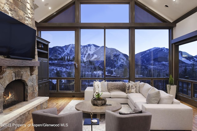 living room with a stone fireplace, a mountain view, hardwood / wood-style floors, and vaulted ceiling