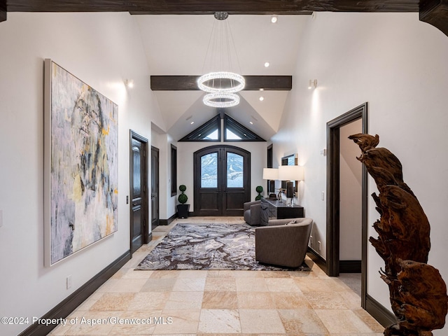 foyer entrance with a chandelier, high vaulted ceiling, and french doors