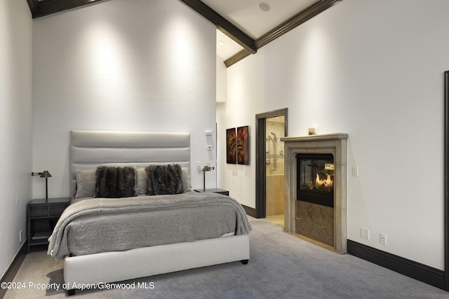 carpeted bedroom with beam ceiling, high vaulted ceiling, and ensuite bath