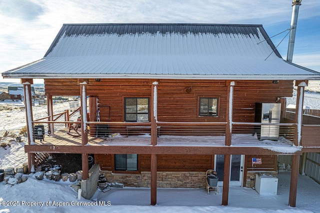 snow covered rear of property with a wooden deck