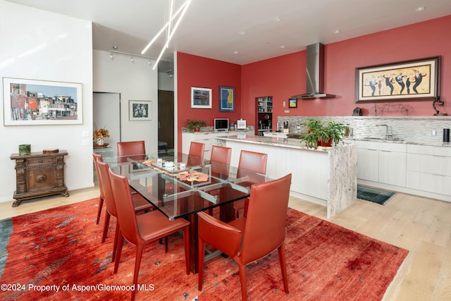 dining area featuring rail lighting, sink, and light hardwood / wood-style flooring