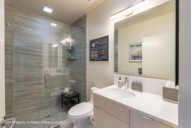 bathroom featuring a shower with door, toilet, and vanity