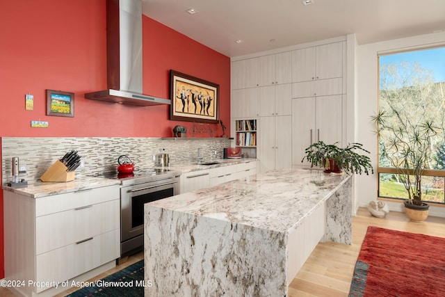 kitchen featuring electric stove, plenty of natural light, light wood-type flooring, and wall chimney range hood