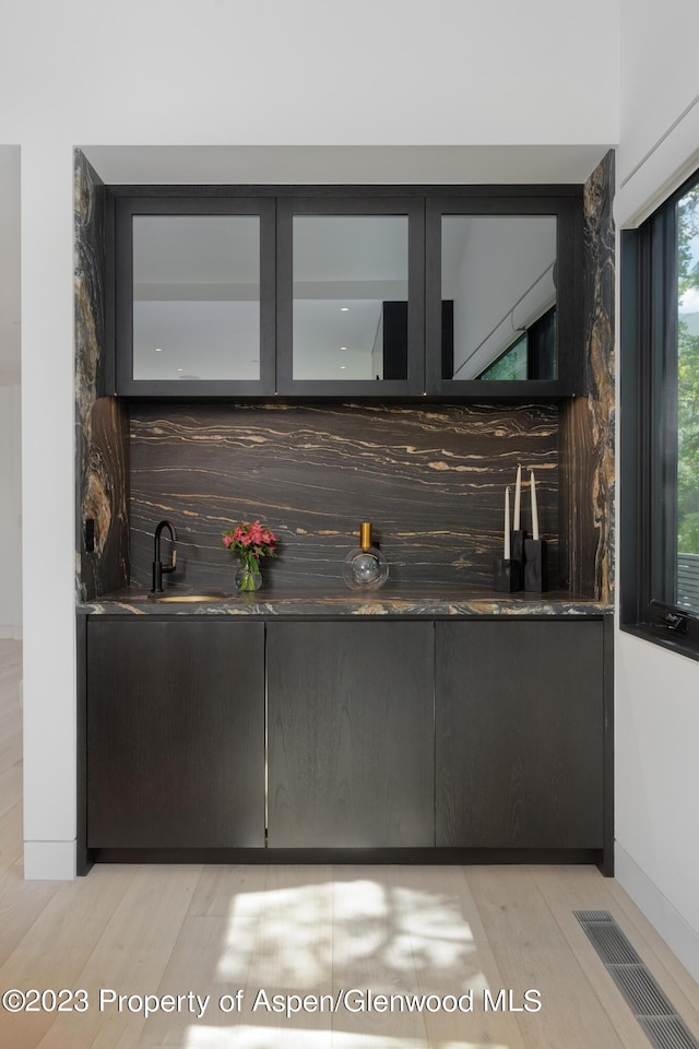 bar featuring light wood-type flooring and sink