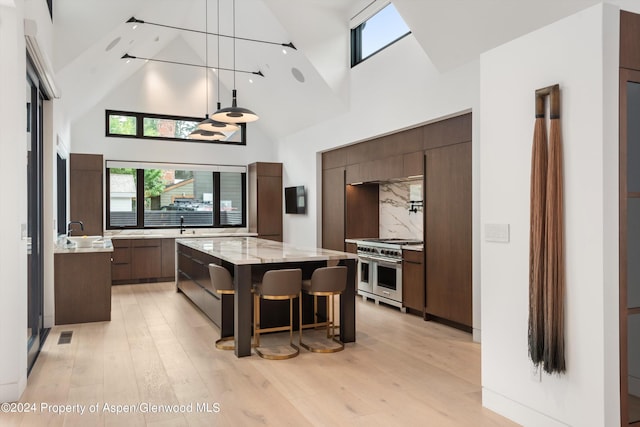 kitchen with a center island, high vaulted ceiling, double oven range, and dark brown cabinetry