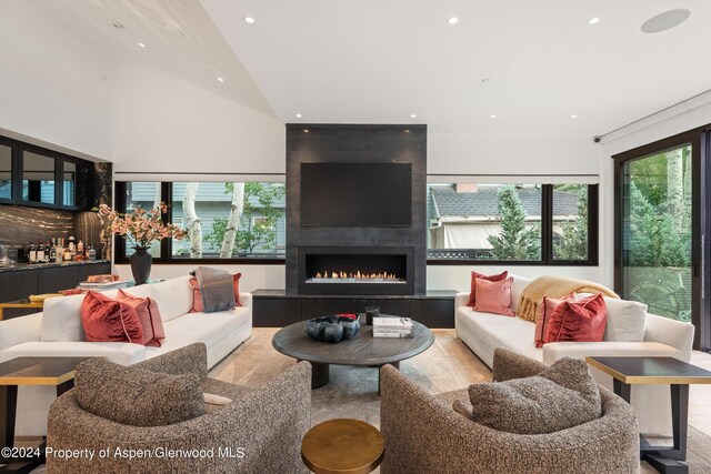 living room featuring a healthy amount of sunlight, vaulted ceiling, and a tiled fireplace