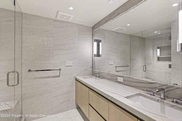 bathroom featuring a shower with door, vanity, and tile walls