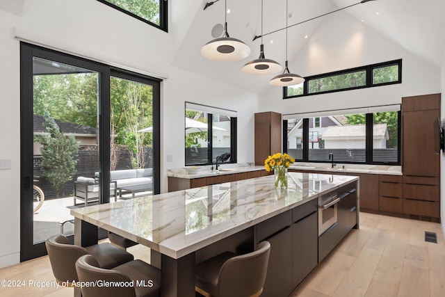 kitchen with light stone counters, a kitchen island, pendant lighting, and a high ceiling