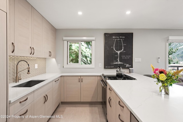 kitchen featuring light brown cabinetry, light stone counters, high end stainless steel range, and sink