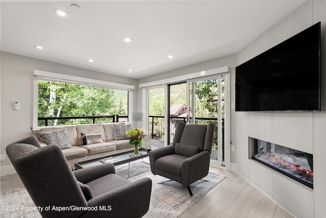 living room with a tile fireplace and light wood-type flooring