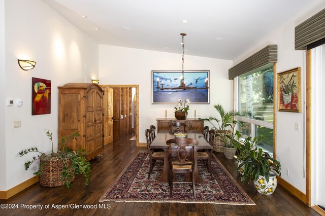 dining room featuring a chandelier, dark hardwood / wood-style floors, and vaulted ceiling