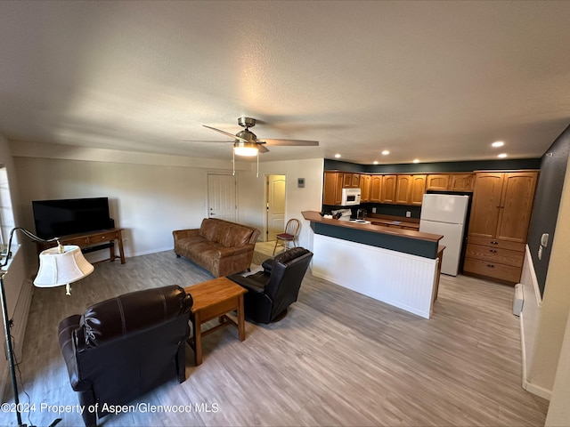 living area featuring ceiling fan, a textured ceiling, recessed lighting, baseboards, and light wood finished floors