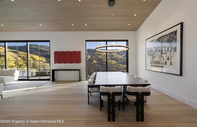 dining room with a mountain view, wooden ceiling, light hardwood / wood-style flooring, and a notable chandelier