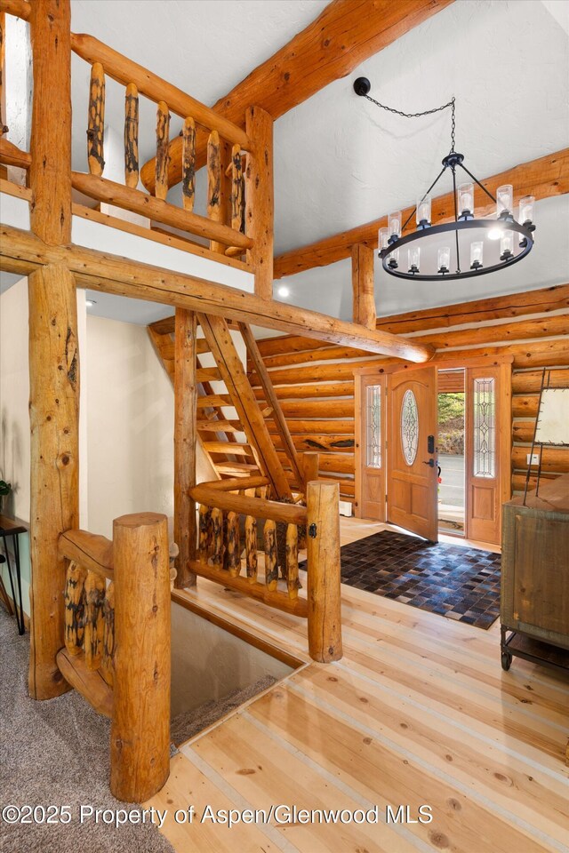 2134 Lower River Rd, Snowmass, CO 81654 - entrance foyer with log walls, a chandelier, beamed ceiling, stairs, and wood-type flooring