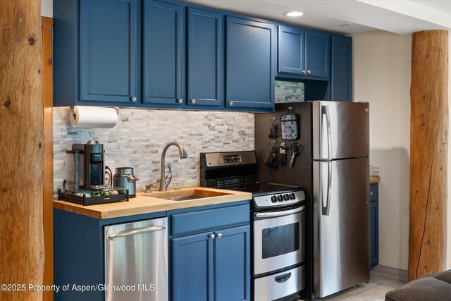 2134 Lower River Rd, Snowmass, CO 81654 - kitchen with blue cabinets, stainless steel appliances, a sink, decorative backsplash, and wood counters
