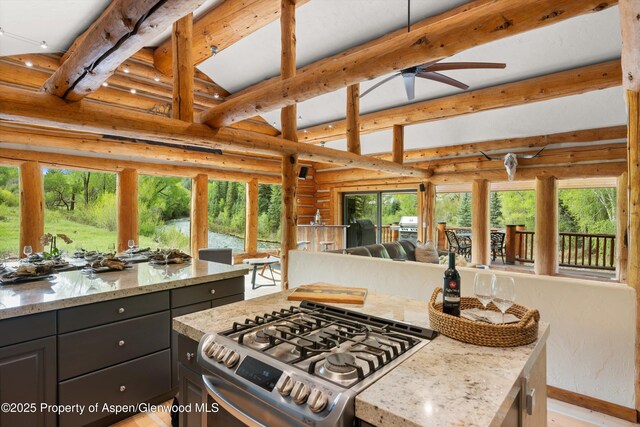 2134 Lower River Rd, Snowmass, CO 81654 - kitchen with stainless steel gas range, beam ceiling, ceiling fan, rustic walls, and light stone counters