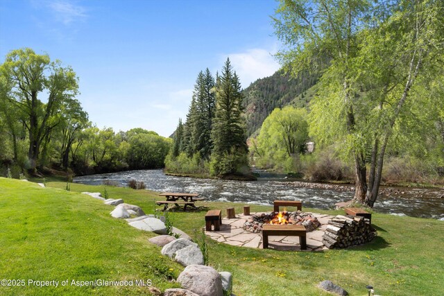 2134 Lower River Rd, Snowmass, CO 81654 - view of grassy yard with an outdoor fire pit, a view of trees, and a water view