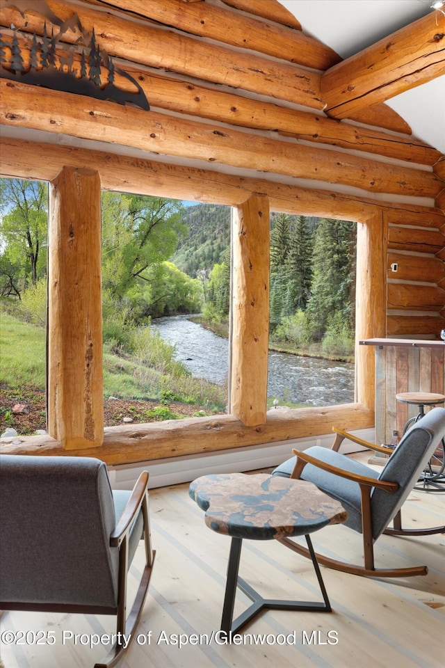 2134 Lower River Rd, Snowmass, CO 81654 - living area with rustic walls, healthy amount of natural light, a water view, and wood finished floors