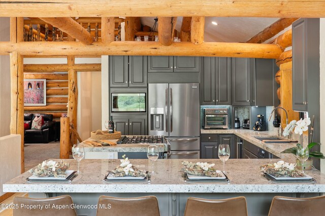 2134 Lower River Rd, Snowmass, CO 81654 - kitchen featuring stainless steel appliances, gray cabinetry, rustic walls, light stone countertops, and a sink