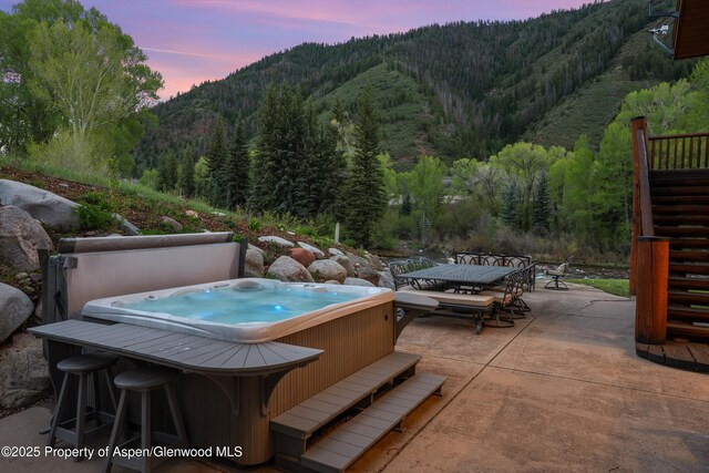 2134 Lower River Rd, Snowmass, CO 81654 - view of patio featuring outdoor dining area, a mountain view, a hot tub, a wooded view, and stairway