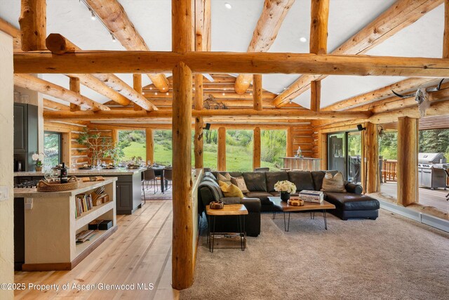2134 Lower River Rd, Snowmass, CO 81654 - living room with rustic walls, beamed ceiling, light wood-style flooring, and high vaulted ceiling