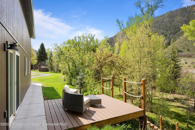 2134 Lower River Rd, Snowmass, CO 81654 - wooden deck featuring a view of trees, a lawn, and a mountain view