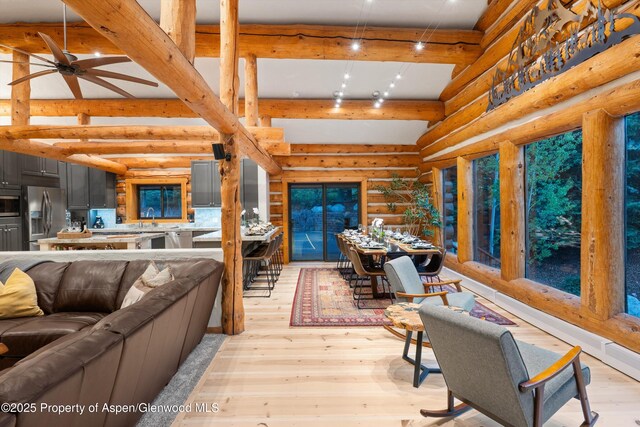 2134 Lower River Rd, Snowmass, CO 81654 - living room featuring beamed ceiling, light wood-type flooring, rustic walls, and ceiling fan