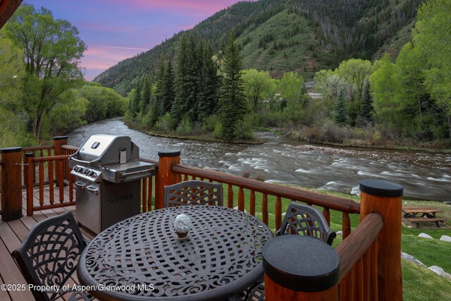 2134 Lower River Rd, Snowmass, CO 81654 - wooden deck featuring a grill, a forest view, outdoor dining space, and a water and mountain view