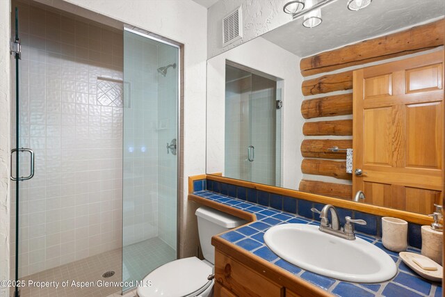 2134 Lower River Rd, Snowmass, CO 81654 - full bathroom featuring a stall shower, toilet, log walls, and vanity
