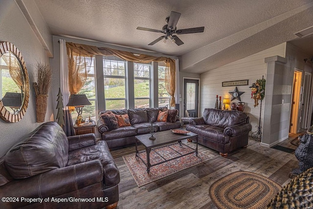 living room with a textured ceiling, lofted ceiling, ceiling fan, and dark wood-type flooring