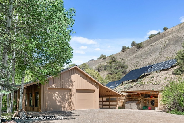 view of front of property with an outbuilding, a mountain view, solar panels, and a garage