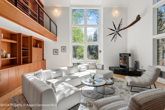 living room with a wood stove, a wealth of natural light, and a high ceiling