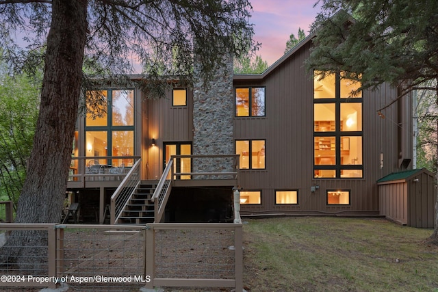 back house at dusk with a yard and a deck