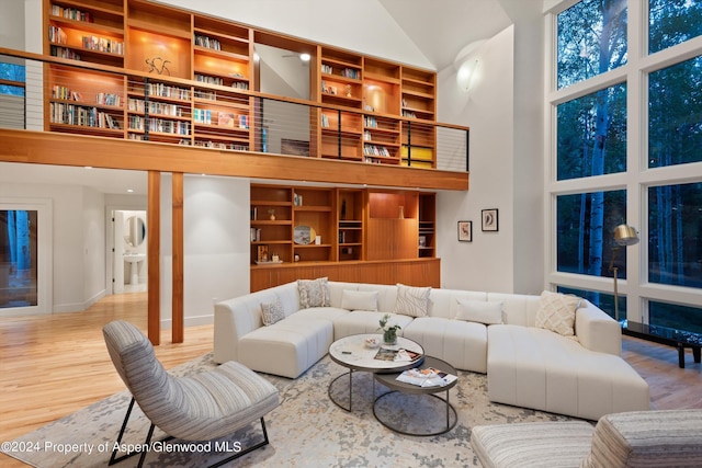 living room with built in features, wood-type flooring, and high vaulted ceiling