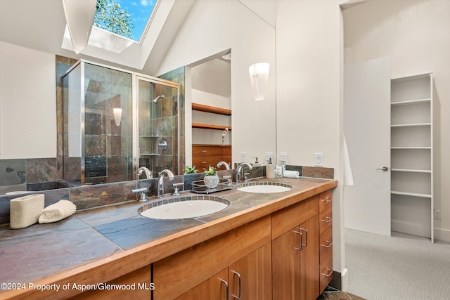 bathroom featuring vaulted ceiling with skylight, vanity, and an enclosed shower