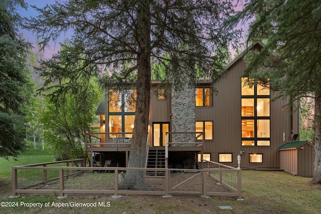 back house at dusk with a lawn and a wooden deck