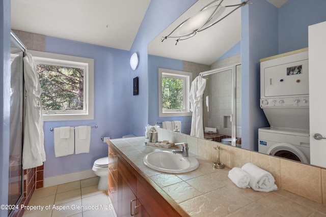 bathroom featuring tile patterned flooring, stacked washer and dryer, vaulted ceiling, and a wealth of natural light