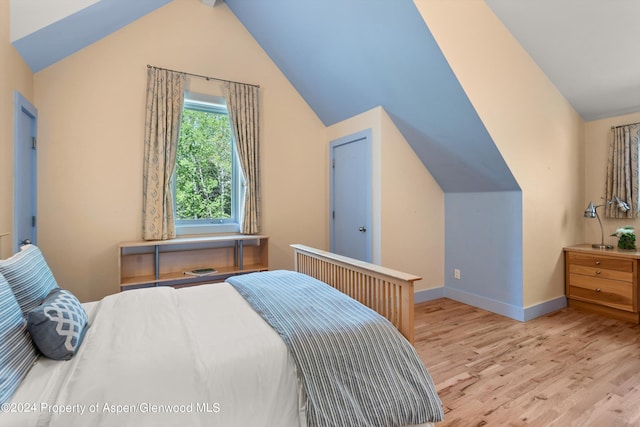 bedroom with light wood-type flooring and lofted ceiling with beams