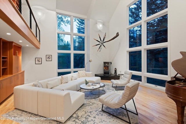 living room with a wood stove, a towering ceiling, and light hardwood / wood-style floors