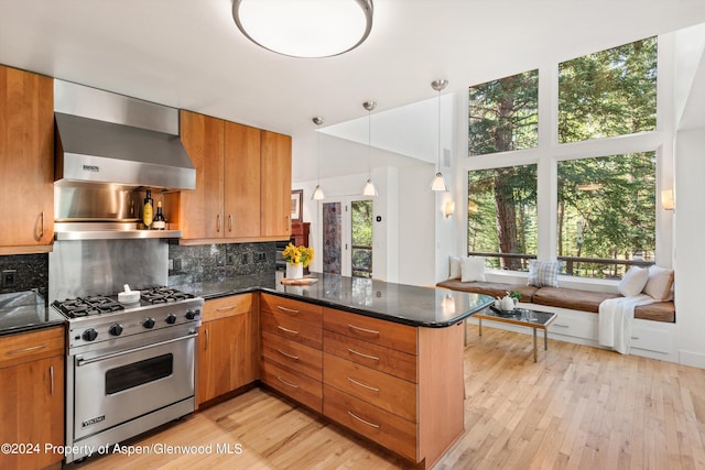 kitchen with luxury range, range hood, backsplash, kitchen peninsula, and pendant lighting