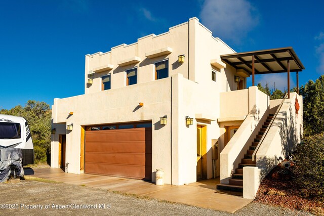 1212 County Road 238th Rd Unit 238, Silt, CO 81652 - pueblo-style house featuring stucco siding, stairs, and an attached garage