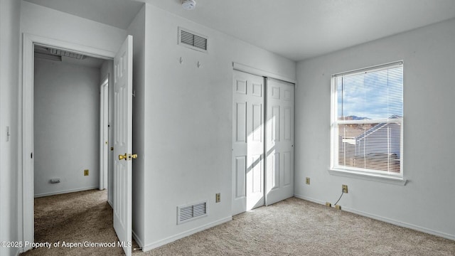 unfurnished bedroom with baseboards, visible vents, a closet, and light colored carpet