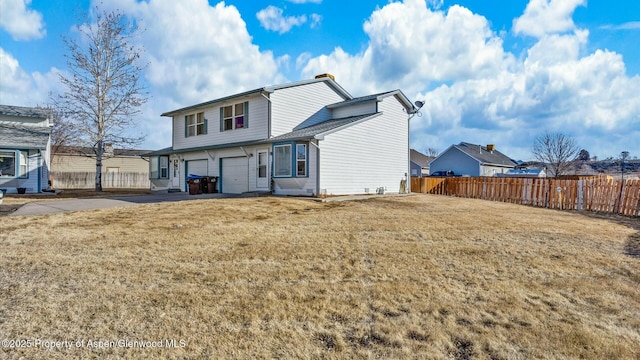 back of property with a garage, fence, and a lawn