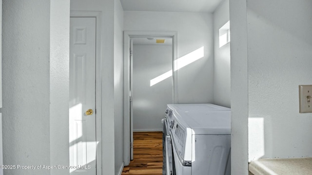 washroom featuring wood finished floors, laundry area, and separate washer and dryer